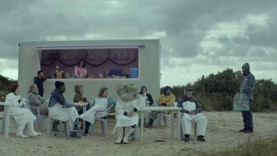 A group of people sitting at a table outside in the film The Silence of the Dying Fish