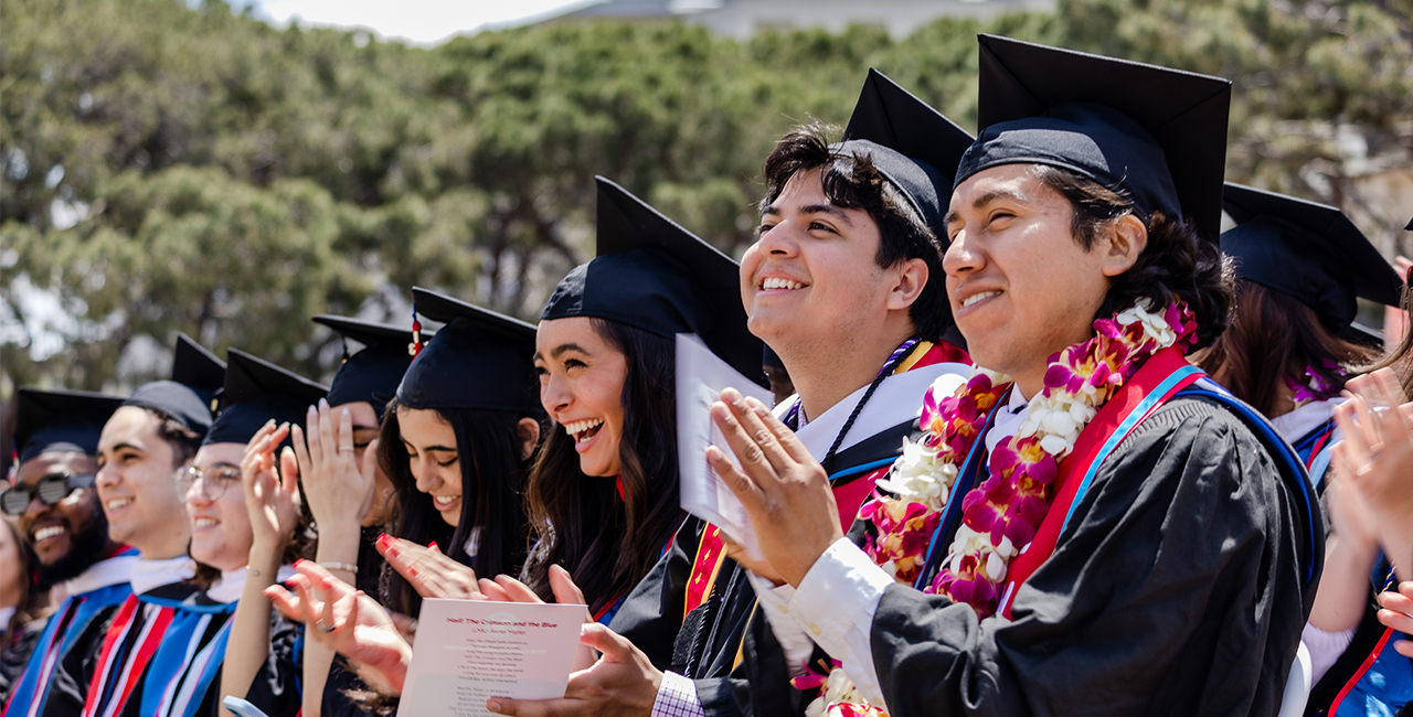 Students smiling and clapping at commencement