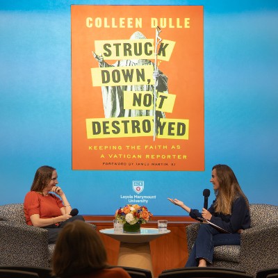 Colleen Dulle and Marissa Papula talking on stage with book cover in background