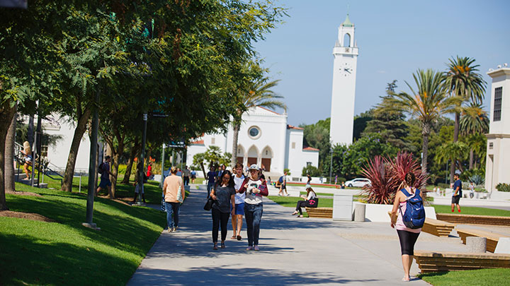 Students walking through Alumni Mall with Sacred Heart Chapel in the distance