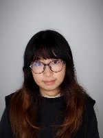 Women with dark long hair and bangs wearing glasses and dark top