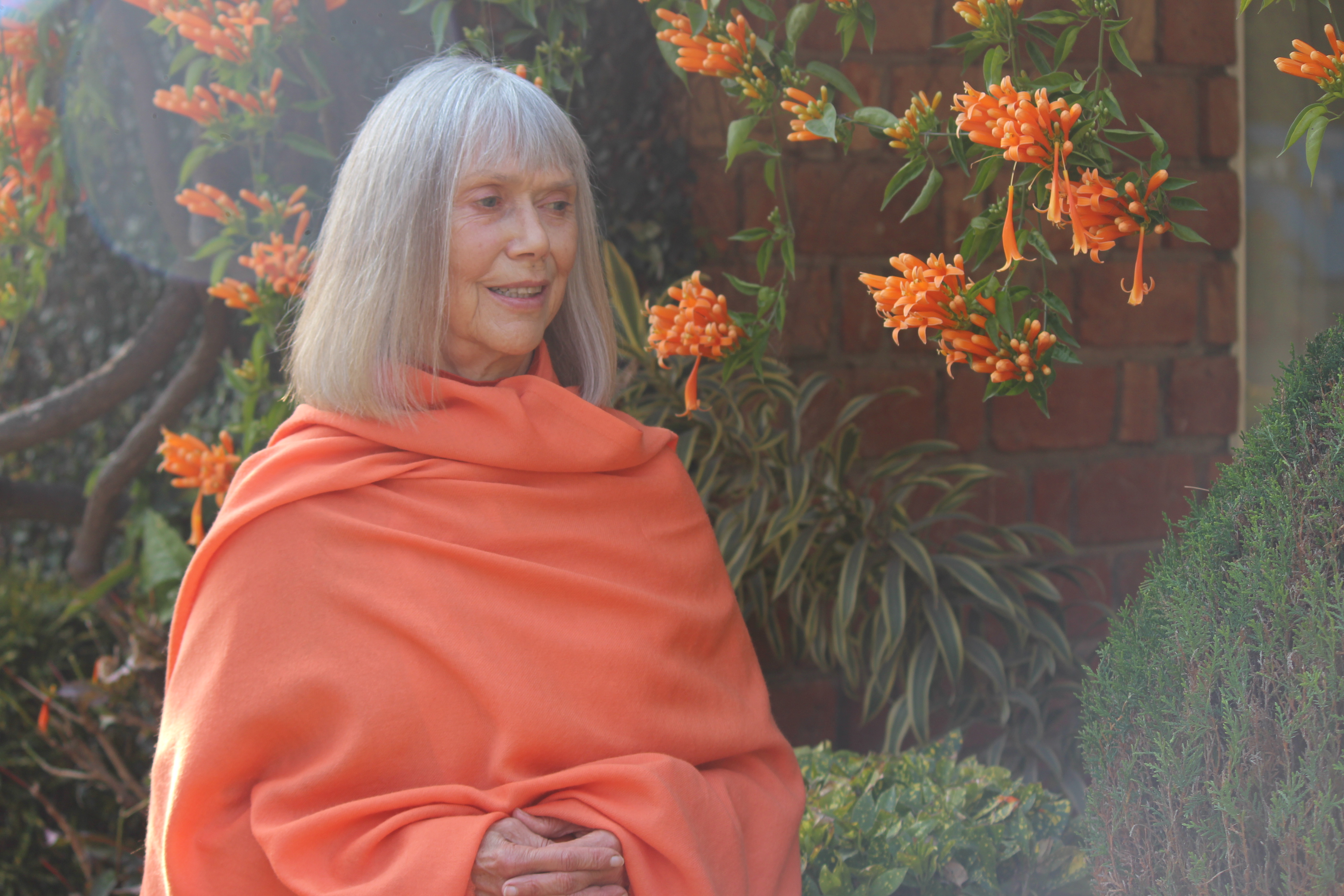  Photo of Swami Ma Radha Bharati sitting in a garden.
