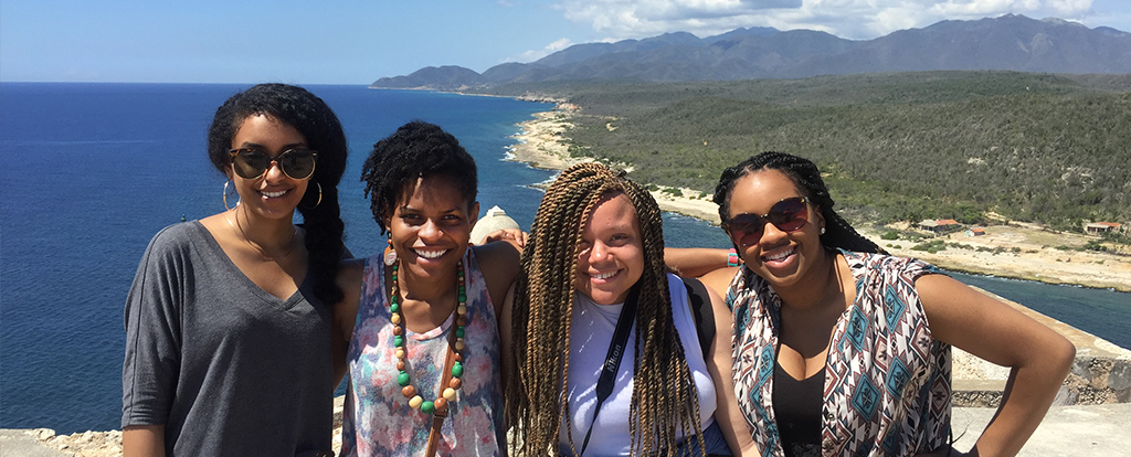 4 students smiling in front of a lake in Cuba