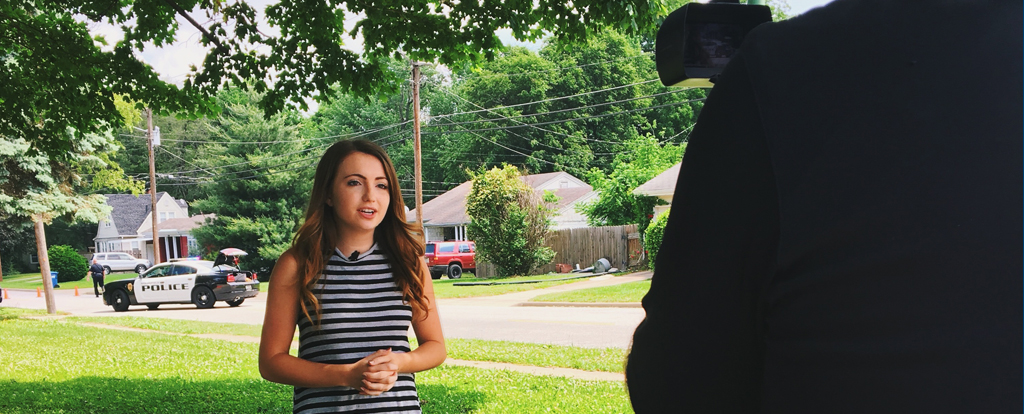 Rachel Haik speaking in front of a camera, on the job at her local news reporting internship