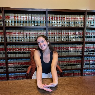 Sadie Nanson black top smiling at desk in front of bookshelves
