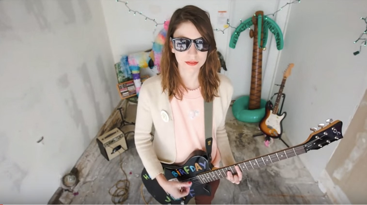 Colleen Green with sunglasses and playing guitar