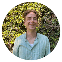 A student smiling in front of green plants