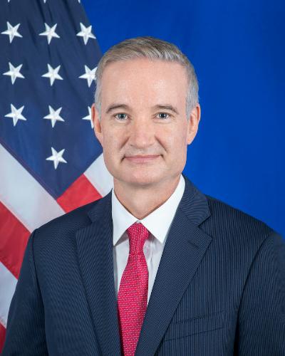 Potrait Photo of Michael Carpet with the flag of U.S. in the background