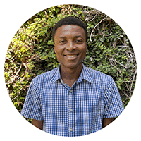 A student smiling in front of green plants